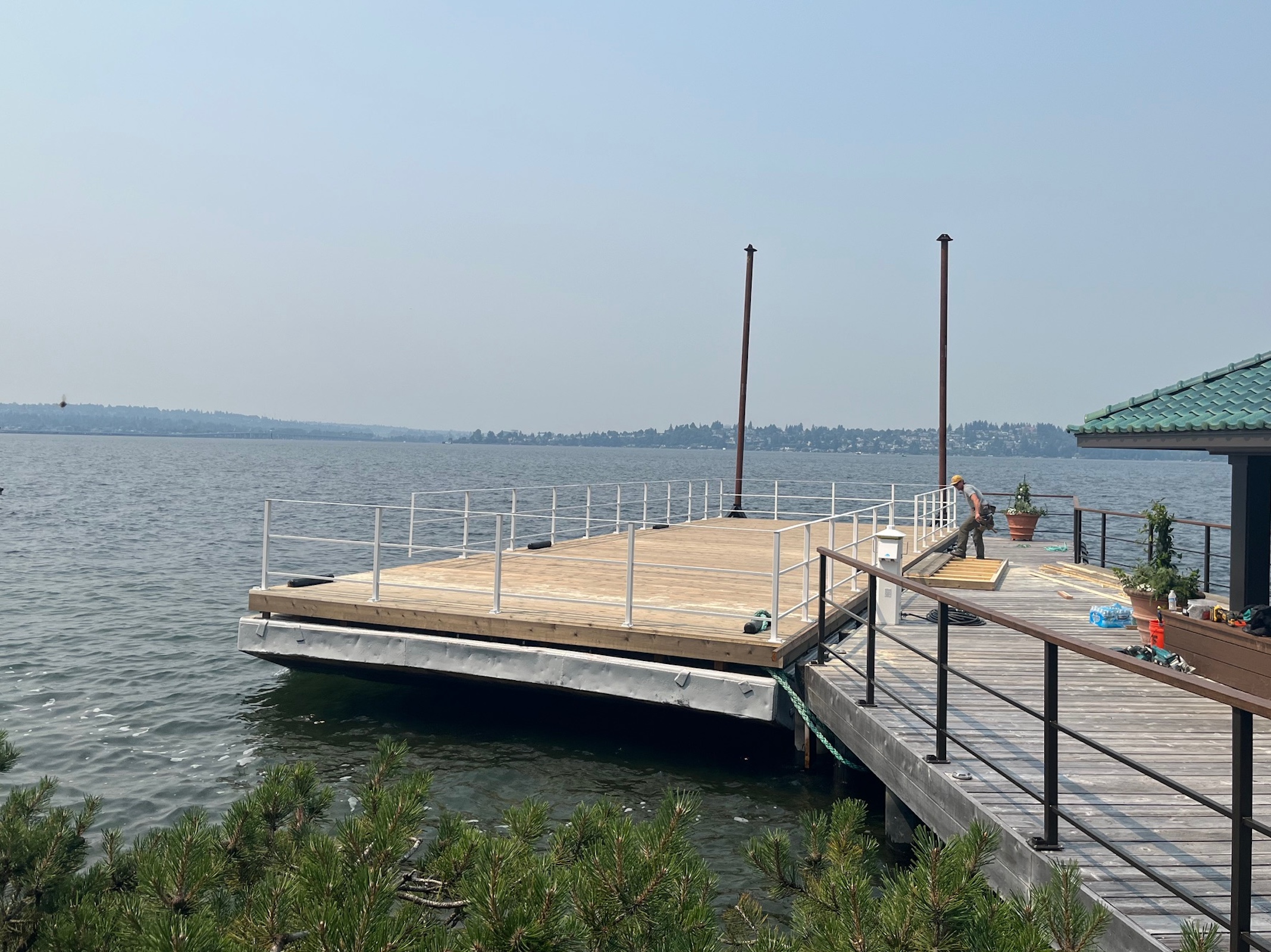 Completed floating event barge with wood deck and safety railings beside a waterfront dock