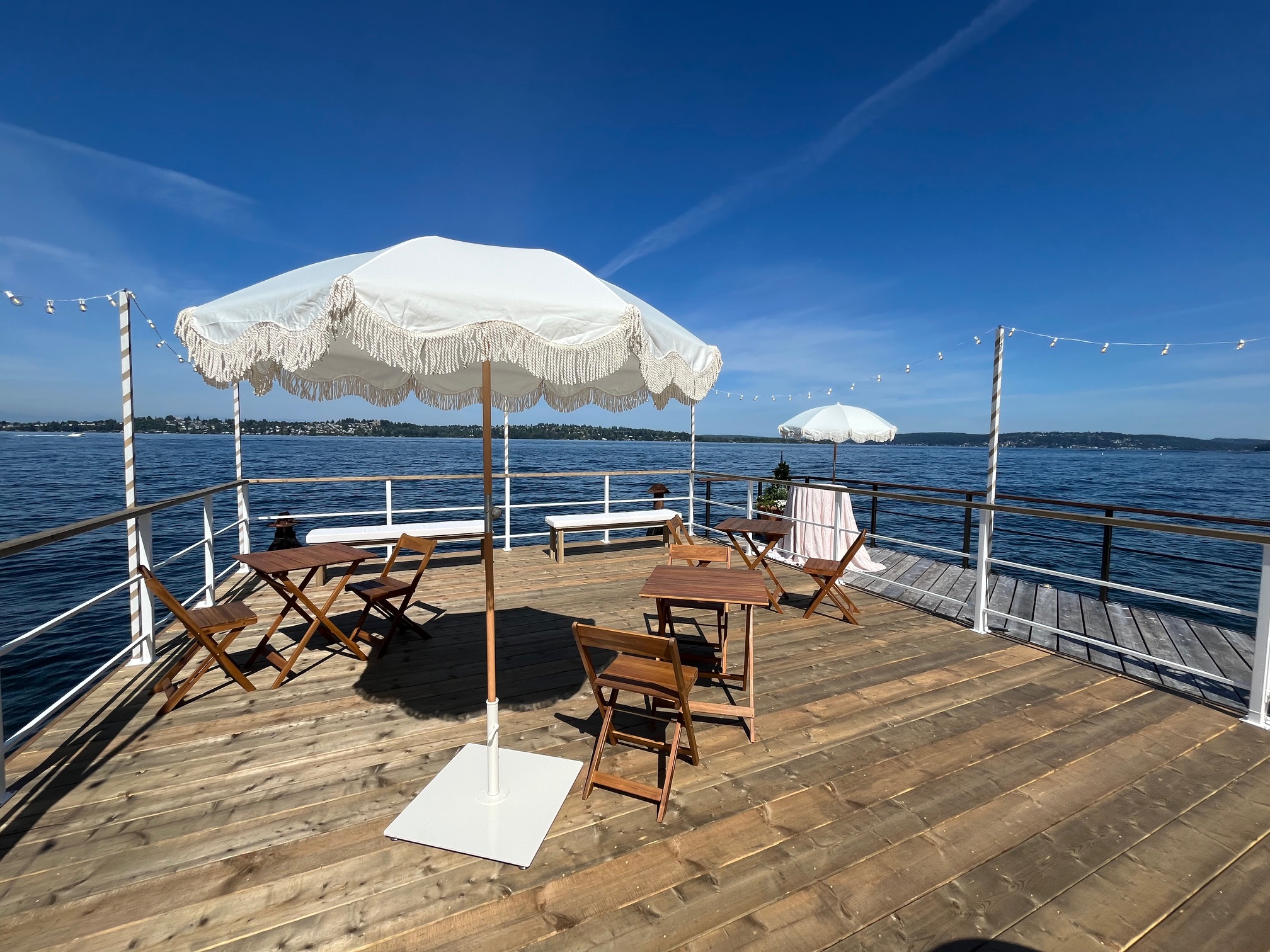 Party barge rental setup with outdoor tables, chairs, umbrellas and wide waterfront views